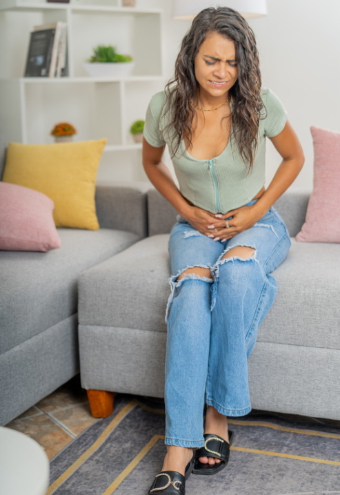 Mujer sentada con las manos en su abdomen por inflamación constante