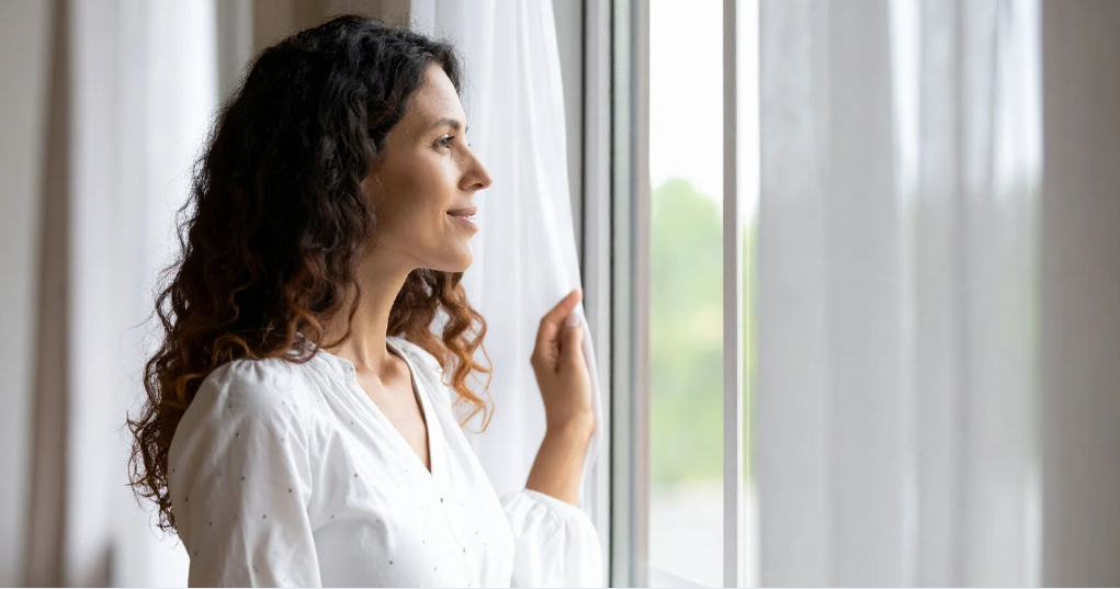 Mujer mira por la ventana preocupada por su estreñimiento